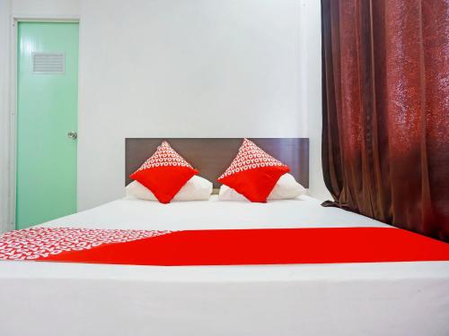 - une chambre avec un lit doté d'oreillers rouges et blancs dans l'établissement OYO 91432 Dalle 5151 Jeneponto, à Pannara