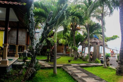a resort with palm trees in front of a building at COCONUT BEACH BUNGALOWs & WARUNG in Amed