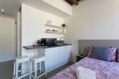 Cet appartement comprend une chambre avec un lit et une cuisine avec des tabourets. dans l'établissement Residenza SubitoSanto - Appartamento con balconcino "3B", à Padoue