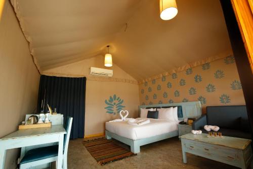a bedroom with a bed and a couch and a table at The Fern Seaside Luxurious Tent Resort Diu in Diu