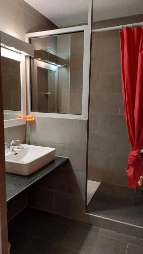 La salle de bains est pourvue d'un lavabo et d'un rideau de douche rouge. dans l'établissement L'Etoile Du Berger, aux Angles