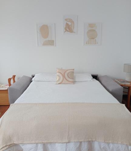 a bed with white sheets and a couch in a room at Pura Playa - Cangas do Morrazo - Primera línea de playa - Rías Baixas - Galicia in Cangas de Morrazo