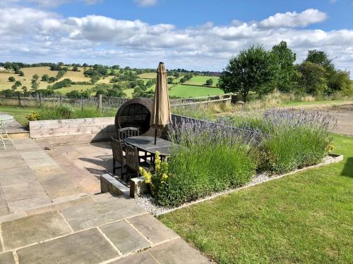 a patio with an umbrella and a bench and a table at Harrogate Barns in Harrogate