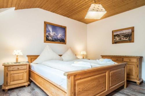 Un dormitorio con una cama grande con sábanas blancas y muebles de madera. en Ferienwohnanlage Oberaudorf, en Oberaudorf