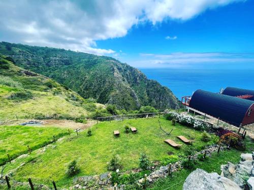 a field with benches on a hill with the ocean at The tiny black bird in Fajã da Ovelha