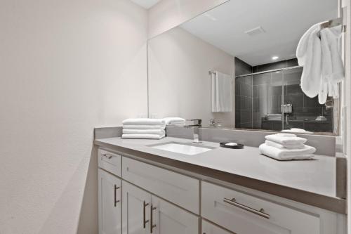 a white bathroom with a sink and a mirror at Abode Houston - Norfolk in Houston