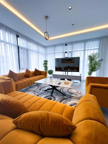 a large living room with a couch and a tv at Olivia Chalet فلة أوليفيا in Al ‘Aqar