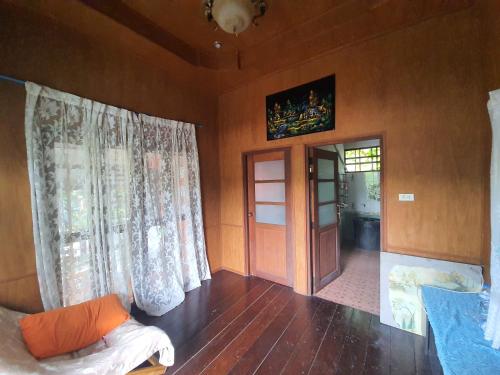 a living room with wooden floors and curtains at Baan Thabthong Homestay (บ้านทับทอง โฮมสเตย์) in Ban Pak Nam