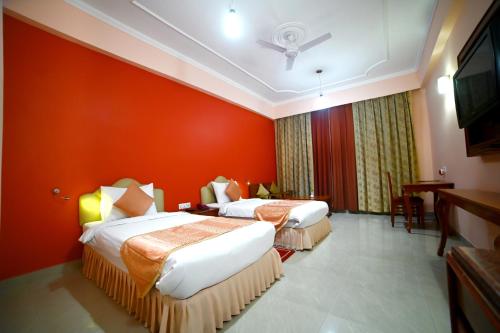 two beds in a hotel room with red walls at The Imperial Bodhgaya in Bodh Gaya
