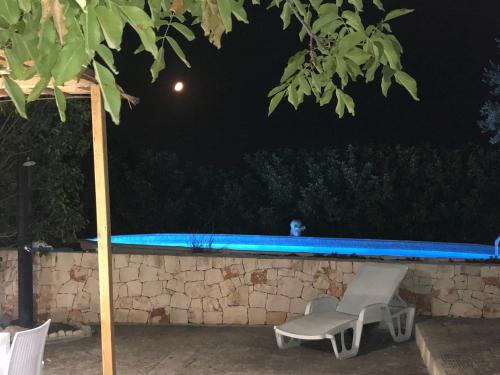 a couple of chairs and a swimming pool at night at Villa Messerà in Martina Franca