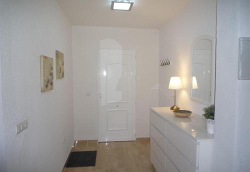 Habitación blanca con tocador con lámpara. en Villa Nala, en Mazarrón