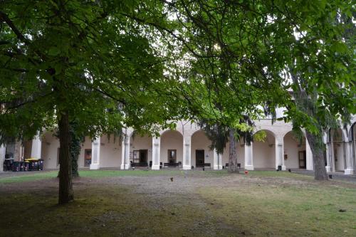 a large white building with trees in the yard at Il Chiostro Hostel and Hotel in Alessandria