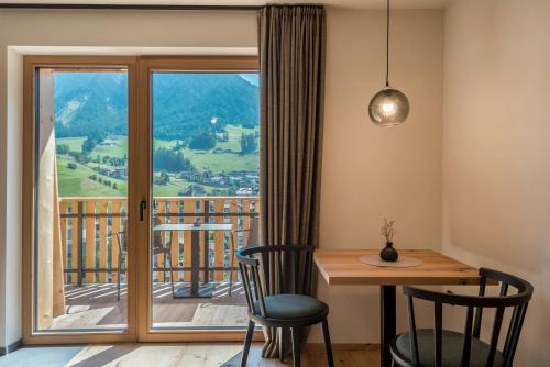 a room with a table and chairs and a balcony at Lippmöshof Apartment Mesdi in Villnoss