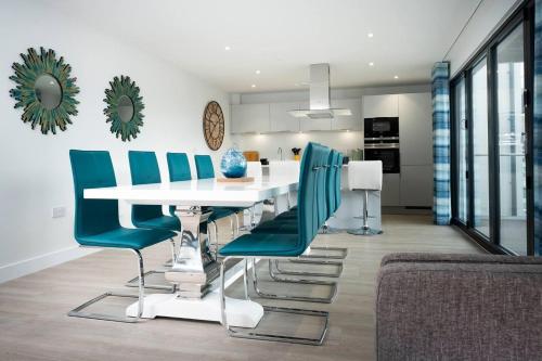 a dining room with a white table and blue chairs at 4br-8guests-balcony-beachview-pool-pets in Woolacombe