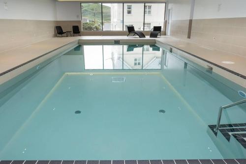a large swimming pool with blue water in a building at 4br-8guests-balcony-beachview-pool-pets in Woolacombe
