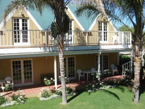 a house with a balcony and palm trees at @Yamkela Guest House in Oudtshoorn