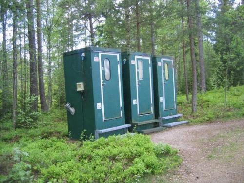three portable toilets are lined up in a forest at Rolfskärrs Stugby in Nygård