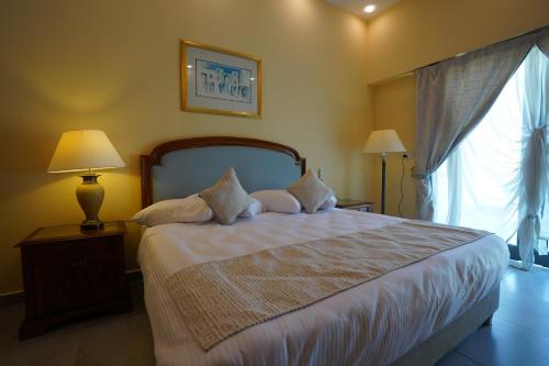 - une chambre avec un lit, deux lampes et une fenêtre dans l'établissement Counsel Beach Hotel New Alamein, à El Alamein