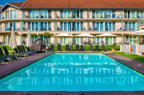a pool in front of a hotel with chairs and umbrellas at Holiday Resorts in Balatonszárszó