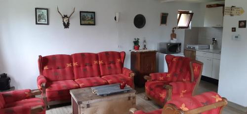 een woonkamer met 2 rode stoelen en een bank bij Stuga Horni Blatna in Horní Blatná