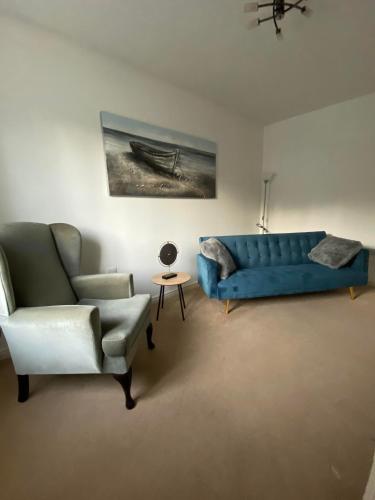 a living room with a blue couch and a chair at Kingfisher House in Mexborough