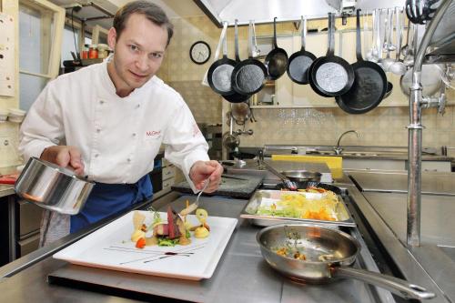 a chef in a kitchen preparing a meal at Hotel-Restaurant Roter Ochsen in Lauchheim