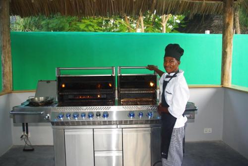 um homem de chapéu de chefs ao lado de um fogão em Princess of Zanzibar em Michamvi