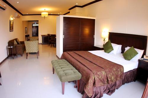 a hotel room with a large bed and a chair at Dreamworld Resort, Hotel & Golf Course in Karachi