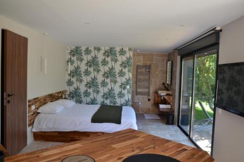 a bedroom with a bed and a large window at Charmant logis neuf équipé/Piscine/SPA/Sauna/Gym 