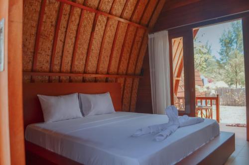 Bett in einem Zimmer mit einem großen Fenster in der Unterkunft Laba Laba Bungalow in Gili Meno