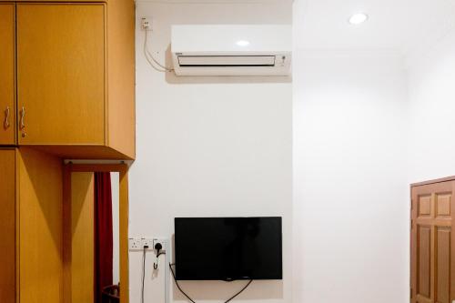 Habitación con TV y aire acondicionado en la pared. en Villa Sri Mayang en Kuala Terengganu