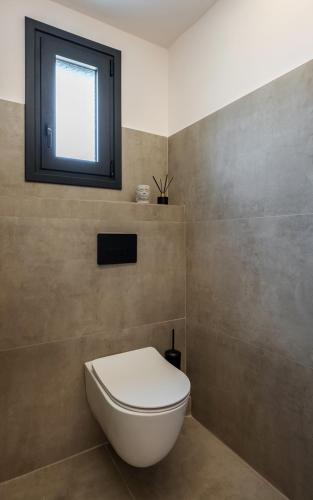 a bathroom with a toilet and a window at Chora Suites, Premium Key Collection in Skiathos Town