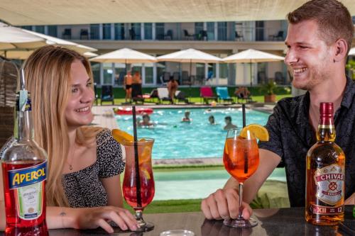 a man and a woman sitting at a table with drinks at Holiday Resorts in Balatonszárszó