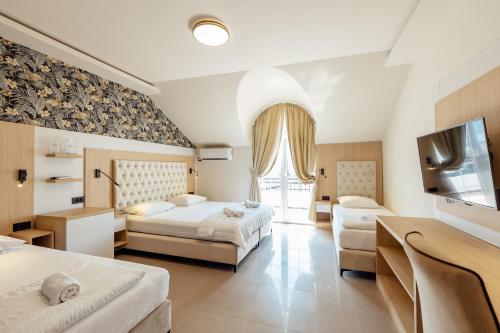 ein Hotelzimmer mit zwei Betten und einem Flachbildfernseher in der Unterkunft Apartments Belani Zelenika in Španjola