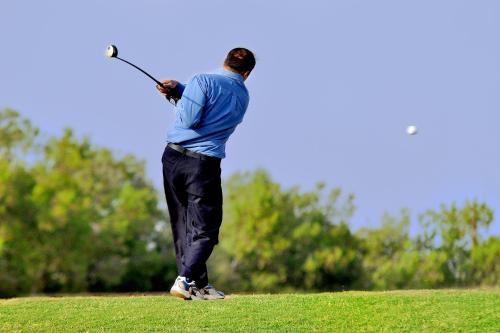 a man swinging a golf club on a field at Dreamworld Resort, Hotel & Golf Course in Karachi