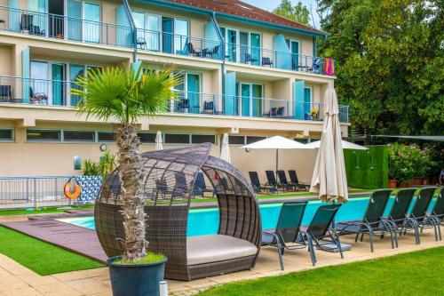 a hotel with a swimming pool with chairs and an umbrella at Holiday Resorts in Balatonszárszó