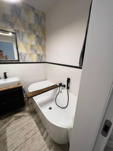 a bathroom with a bath tub and a sink at Uroczy apartament z ogrodem in Rumia