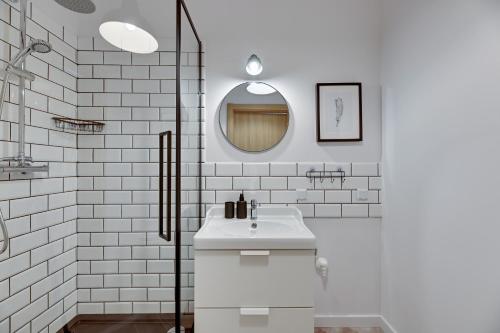 W białej łazience znajduje się umywalka i lustro. w obiekcie Bastion Wałowa Comfort Apartments w Gdańsku