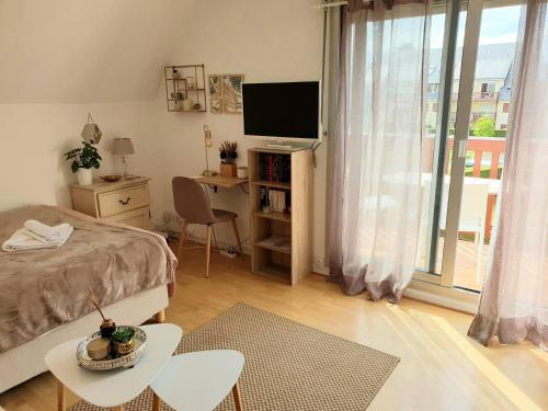 - une chambre avec un lit et un bureau avec une télévision dans l'établissement Chez Romy - studio équipé avec wifi - proche plage Deauville, à Tourgéville
