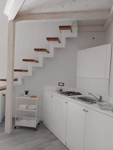 a white kitchen with a staircase in the wall at Fradalisa Delizioso monolocale a Vico Equense in Vico Equense