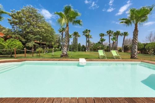 a swimming pool with two chairs and palm trees at Dependance di Villa Dea by BarbarHouse in Matino