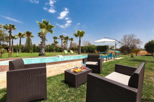 a pool with wicker chairs and a table next to it at Dependance di Villa Dea by BarbarHouse in Matino