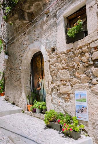 a man standing in the doorway of a stone building with flowers at Dimora Cavour in Amantea