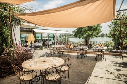 a patio with tables and chairs with a view of a river at Le Ali Del Frassino in Peschiera del Garda