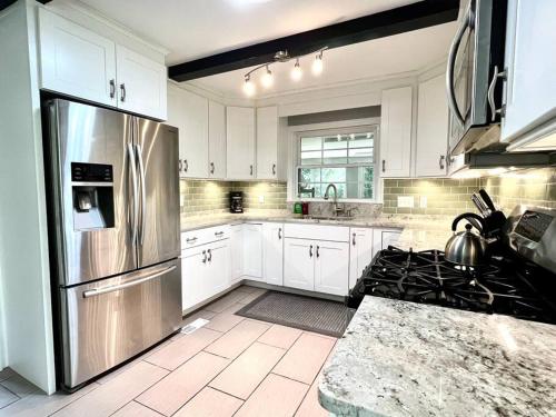 a kitchen with white cabinets and a stainless steel refrigerator at The Best Family & Friends Hangout & Pet Friendly!! in Wilmington