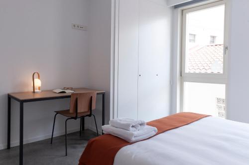 a bedroom with a bed and a desk and a window at HomeSanGil in Burgos