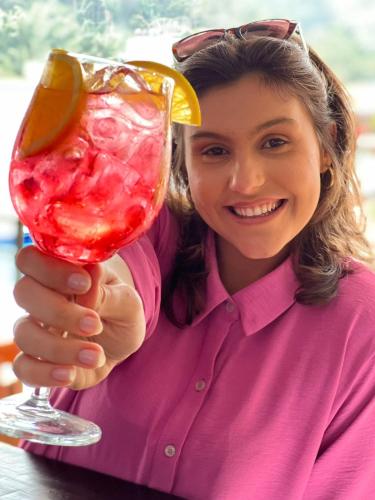 a woman is holding a drink with a lemon slice at Bliss Hotel Vale do Café in Vassouras