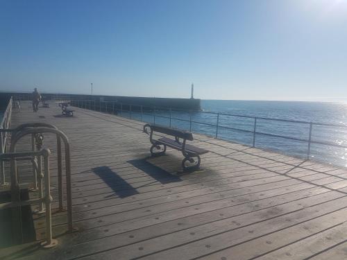 a bench on a pier next to the ocean at Lovely Seafront 2 bed flat in Aberystwyth in Aberystwyth