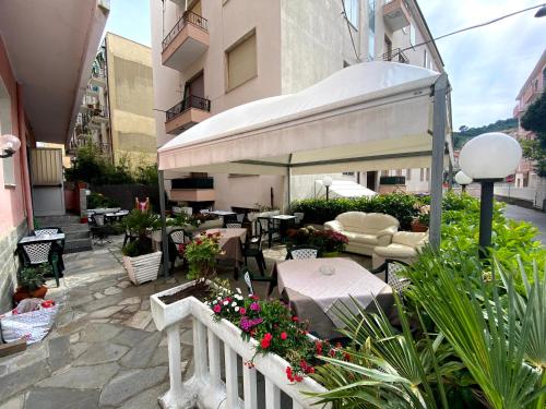 an outdoor patio with tables and chairs and flowers at Hotel Riz in Finale Ligure