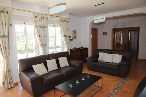 a living room with a leather couch and a table at Villa Meretseger in Almogía
